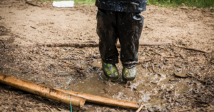 Child jumping in mud in wellies